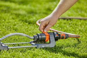 a man is trimming the grass with a garden hose