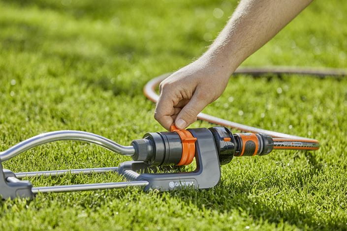 a man is trimming the grass with a garden hose