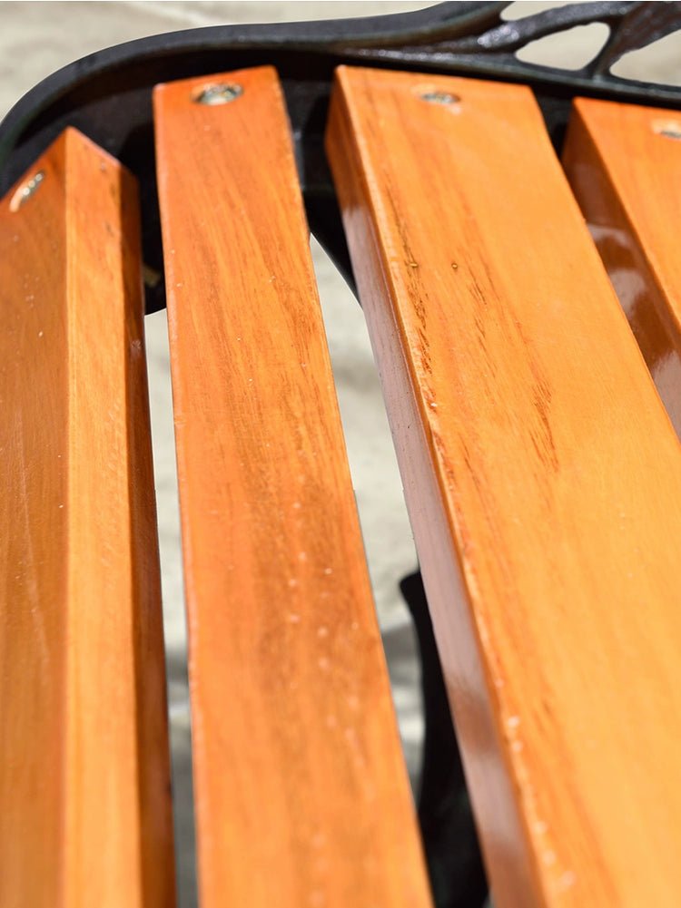 a close up of a wooden bench on a sidewalk