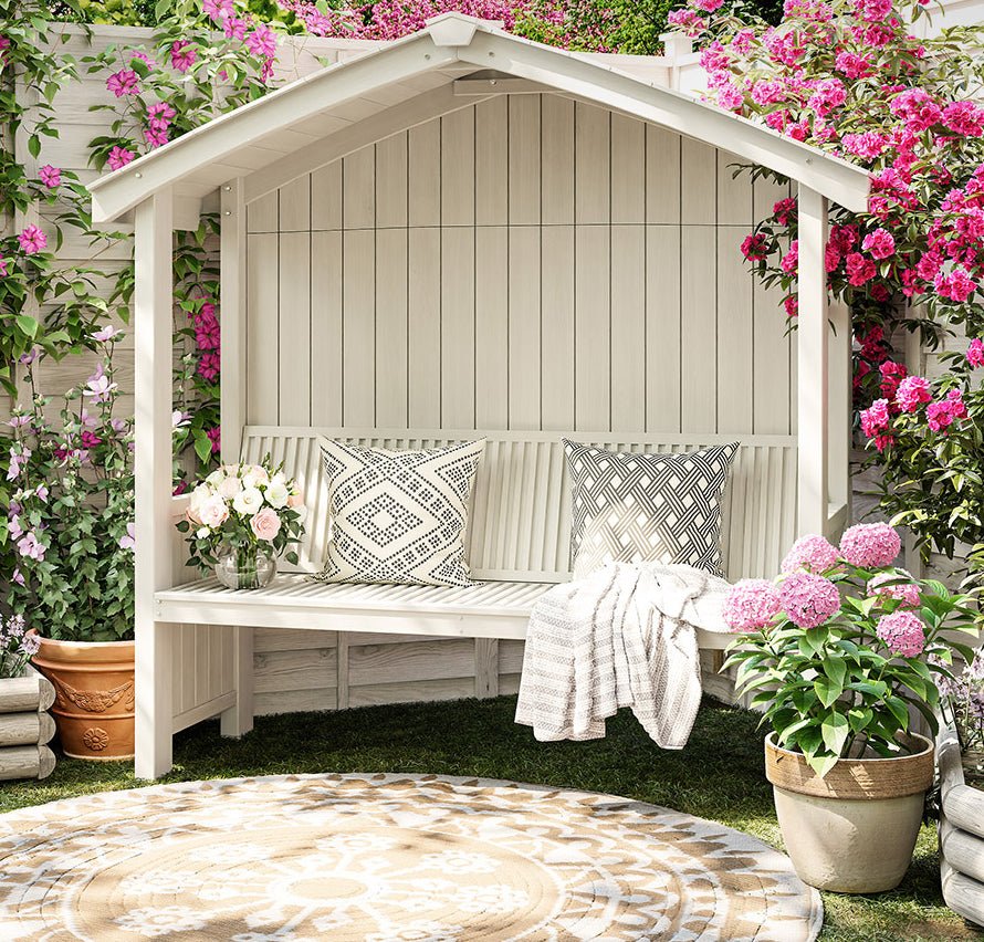 a white bench sitting next to a bunch of flowers