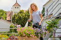 a woman is watering flowers in a pot