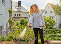 a woman is watering flowers in a garden